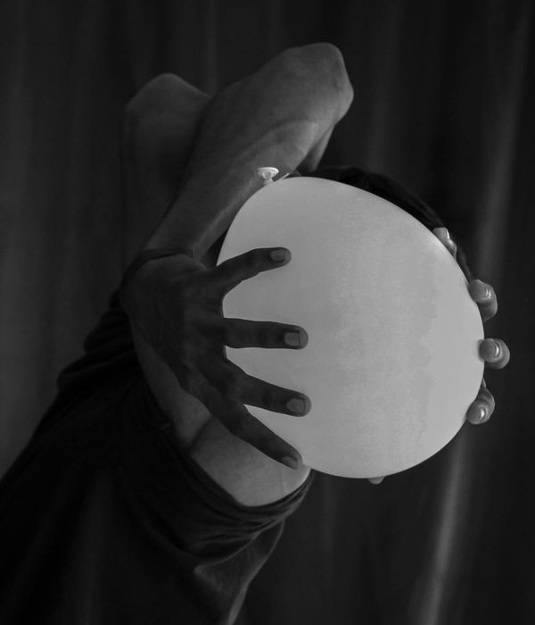 Man holding a difficult static strength pose in a dark room.